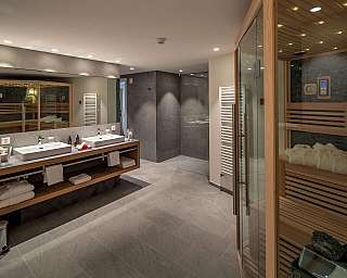Spacious bathroom featuring sinks, sauna, and elegant decor.