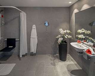 Spacious bathroom with shower, sink, and decorative flowers.