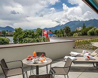 Balcony overlooking mountains and lake with breakfast setup.